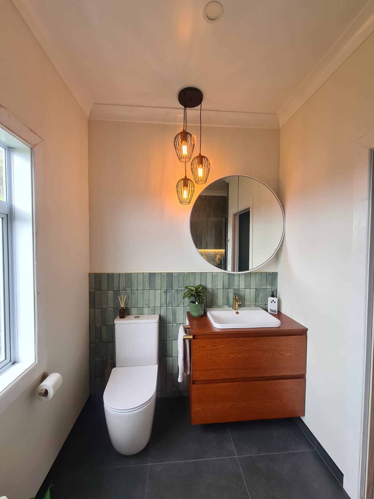 Green zellige bathroom with timber vanity and round mirror