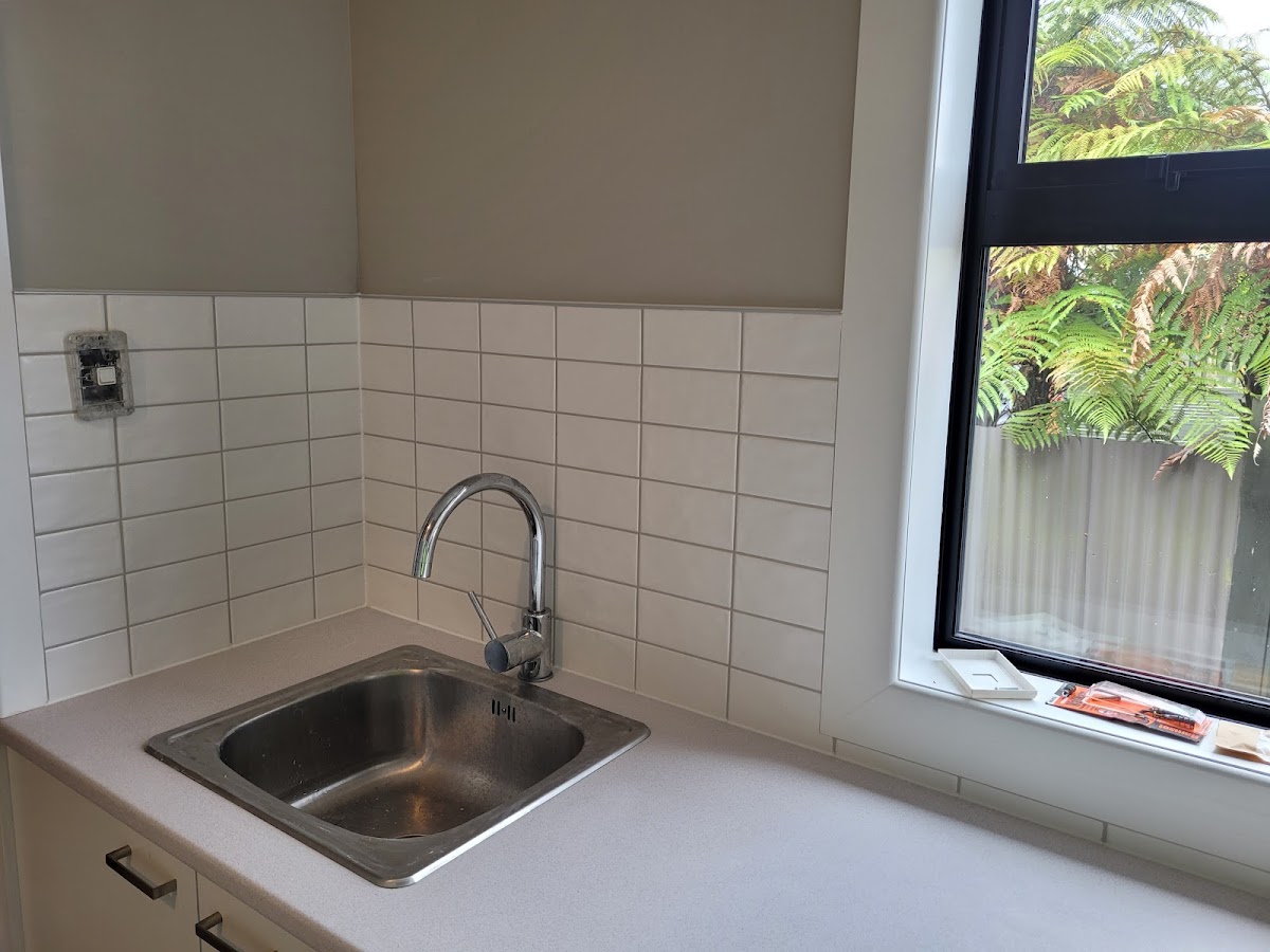 White subway tiling in a kitchen corner beside a fern outlook